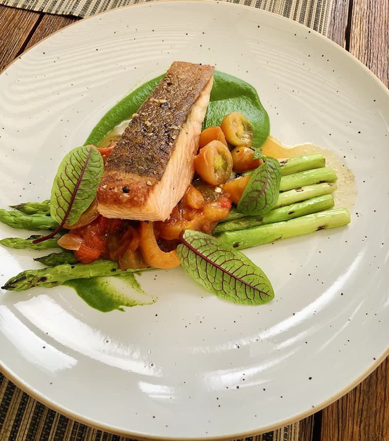 A plated salmon fillet with tomatoes and asparagus